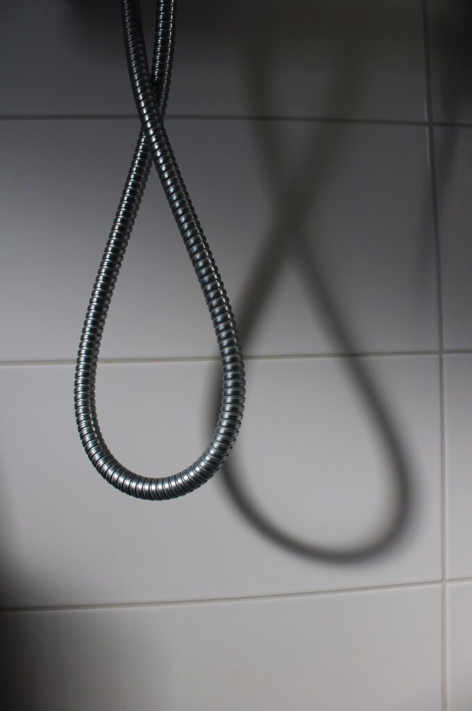 The shadow of a metal cord from a shower nozzle forms an infinity symbol