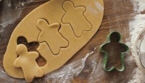 Cookie dough with three gingerbread-man shapes cut out of it