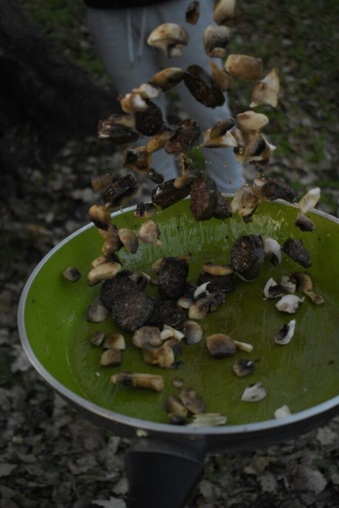 Chopped mushrooms falling into a green skillet