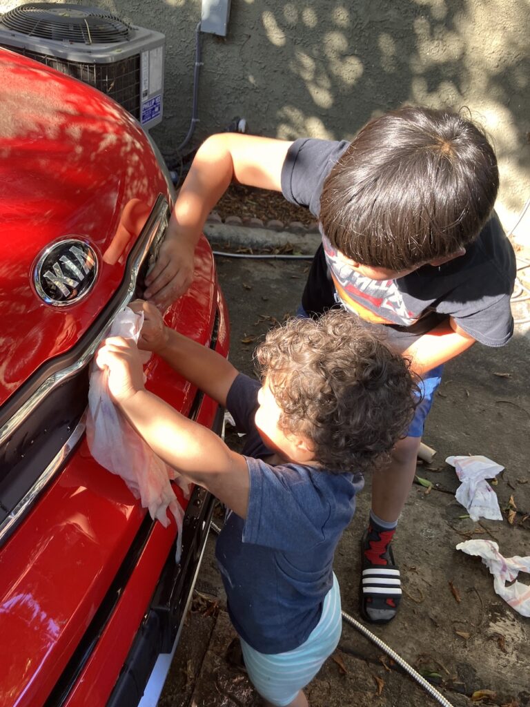 A 9-year-old and a toddler wash a red Kia